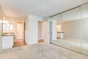 an empty living room with mirrored closet doors and a kitchen at Veranda La Mesa, La Mesa, California